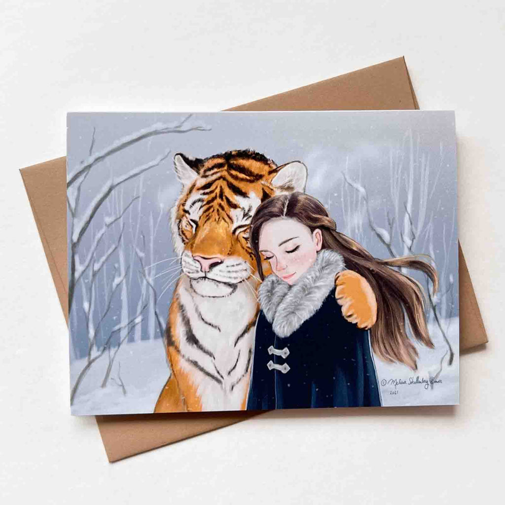 a notecard featuring a girl embracing her tiger best fried in a snowy background