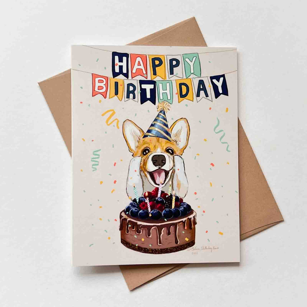 This greeting card features a Corgi dog in front of a birthday cake