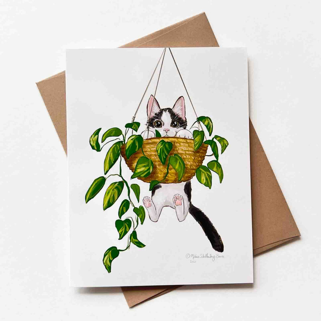 this funny notecard features a grey and white cat is dangling from a hanging planter