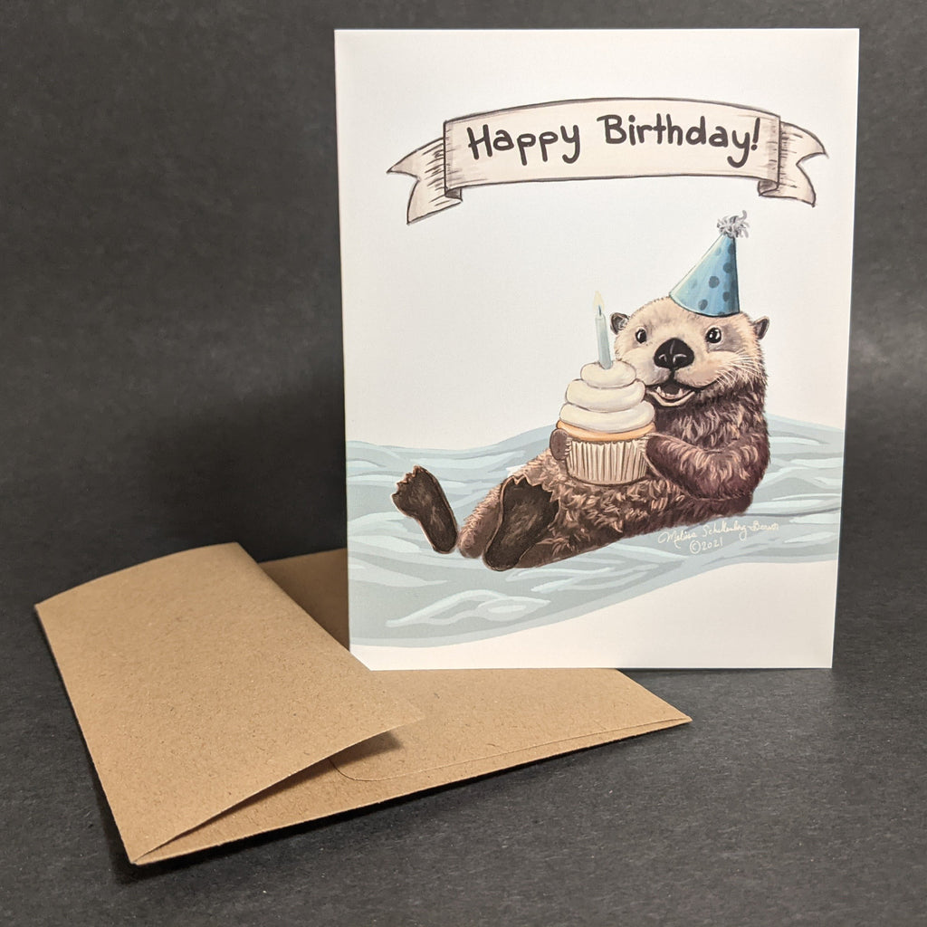 a happy sea otter floating in the water with a cupcake on his belly